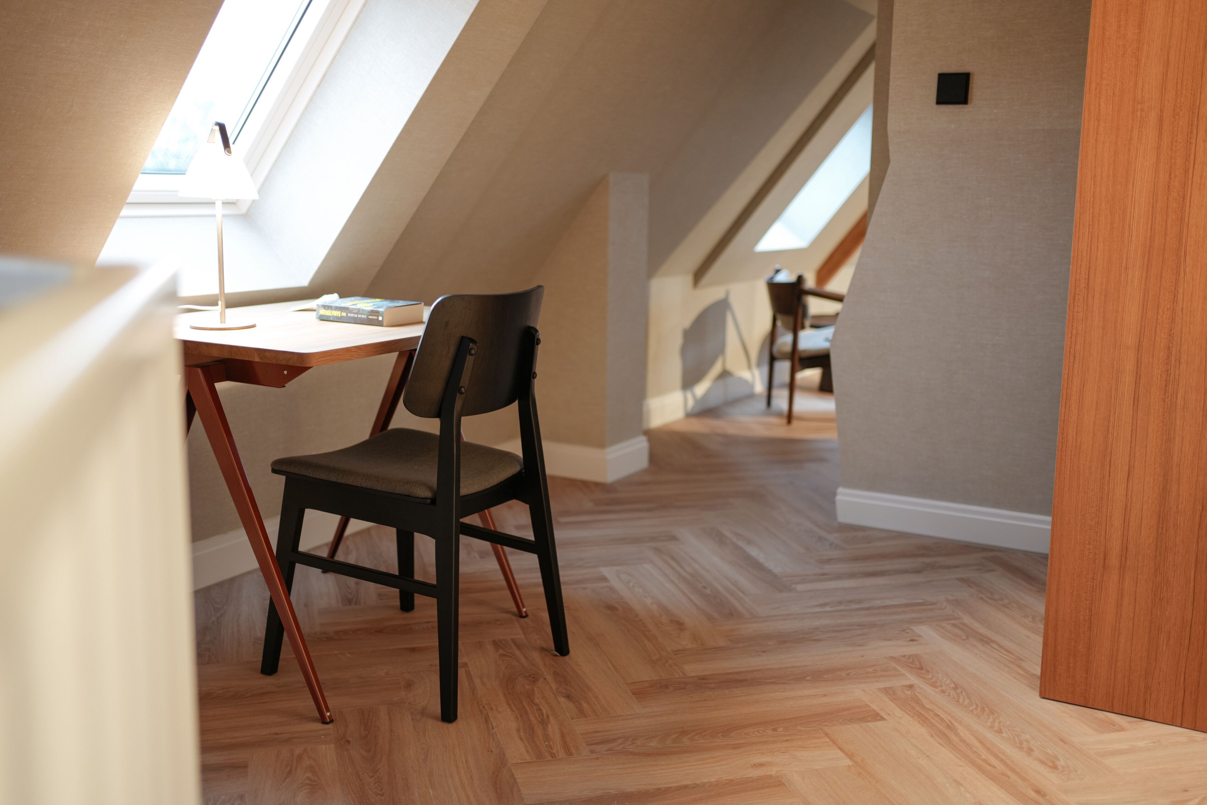 Une chambre de style loft moderne, avec un plafond en pente, un plancher en bois et un bureau avec une chaise.