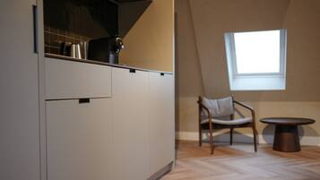 A modern kitchen with a built-in stove, a window, and a dining area with a chair and table.