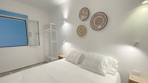 Et soveværelse med seng, garderobeskab, walk-in closet og vægmonterede lamper.