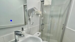 Et moderne badeværelse med vask, toilet og brusekabine med glasvægge.