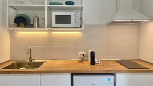 Et moderne køkken med hvide skabe, en stålvask, en mikrobølgeovn og en integreret opvaskemaskine.