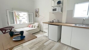 A compact kitchen with white cabinets, a wooden countertop, and a built-in microwave. - Eden Gomera Suite (Lepe)
