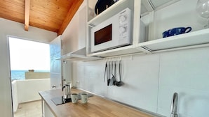 A modern kitchen with a wooden ceiling, white cabinets, a microwave, and a view of the sea. - Eden Gomera Terrace Apartment oceanviews (Lepe)