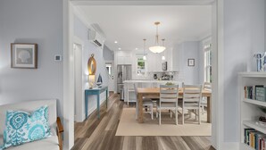 A modern kitchen with white cabinets, a wooden dining table, and pendant lighting. - *New* Beach Hair Don't Care, hot tub, close to pool (Pacific Beach)