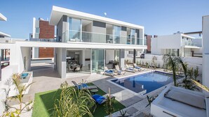 A modern two-story house with a swimming pool, outdoor seating, and a well-maintained garden. - Olivine Sea Pearl Villa #18 (Paralimni)
