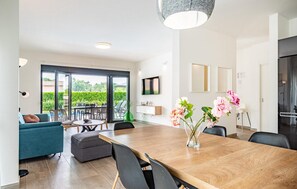 Relax in this stylish dining area with a long table, comfortable sofa, and flat-screen TV.