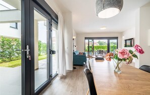 Relax in this stylish living space with a sofa, dining table, and floor lamp, leading to an outdoor area through a large sliding glass door.