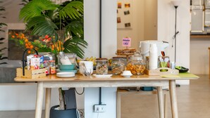 A kitchen counter with various food items and kitchenware, including a sign that says "BANANA CAKE". - Chamemon Bed Phuket Town (Phuket)