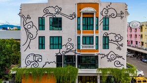 A building with a unique exterior featuring artistic fish and wave designs. - Chamemon Bed Phuket Town (Phuket)