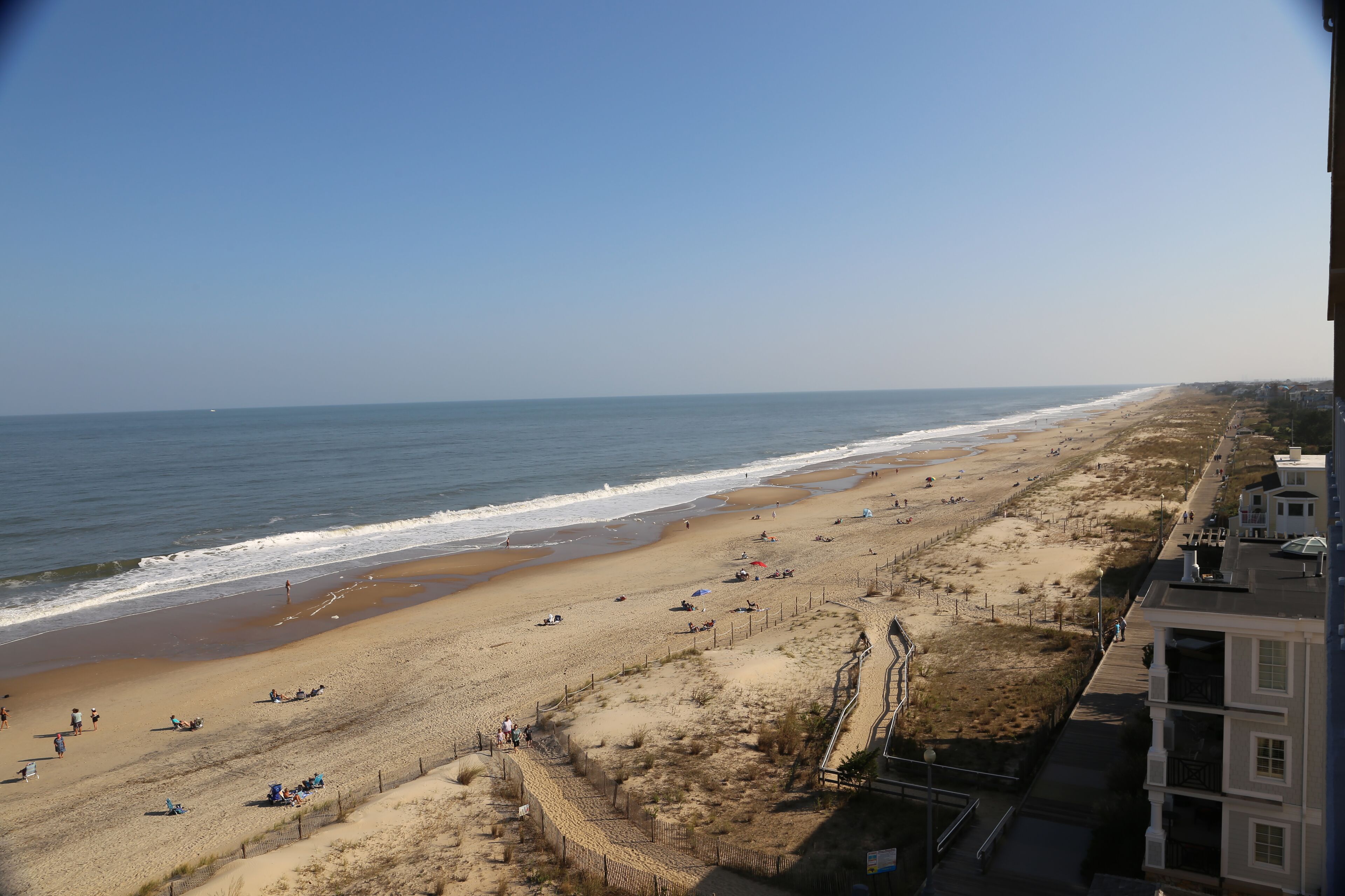 Uma praia com uma cerca delimitando a areia do calçadão.