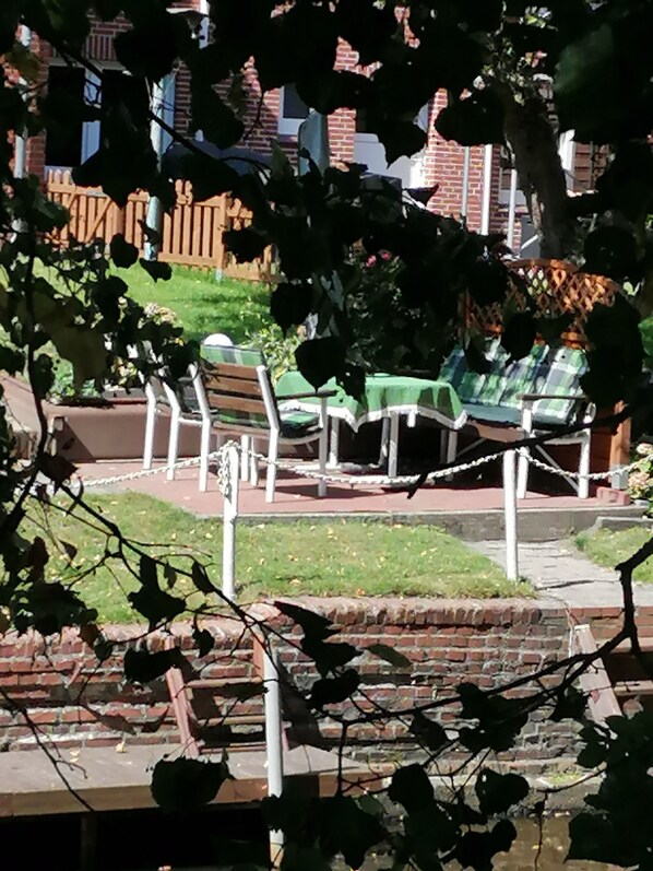 A brick wall with a green lawn and a picnic table with chairs.