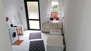 Un espacio habitable compacto con lavadora, radiador y una pequeña mesa.