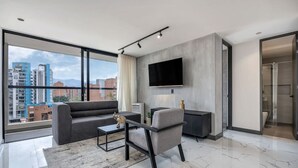 A modern living room with a sofa, a coffee table, and a TV mounted on the wall.