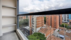 A balcony with a view of a cityscape, featuring multi-story buildings and a clear sky.