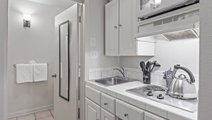 A compact kitchen with white cabinets, a double sink, and a stove.