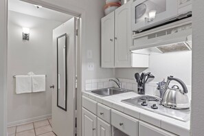 A compact kitchen with white cabinets, a double sink, and a stove. - Quiet End, Ground Floor, Ski Bus | Sleeps 4 | Moose Mgt 805 (Park City)