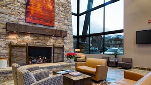 A spacious lobby with a stone fireplace, leather sofas, and a large window offering a view of the outside.