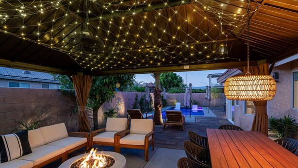 Une terrasse extérieure dotée d’un foyer, d’un espace salon et de guirlandes lumineuses.