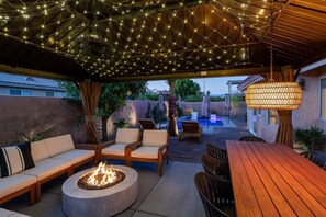 Une terrasse extérieure dotée d’un foyer, d’un espace salon et de guirlandes lumineuses.