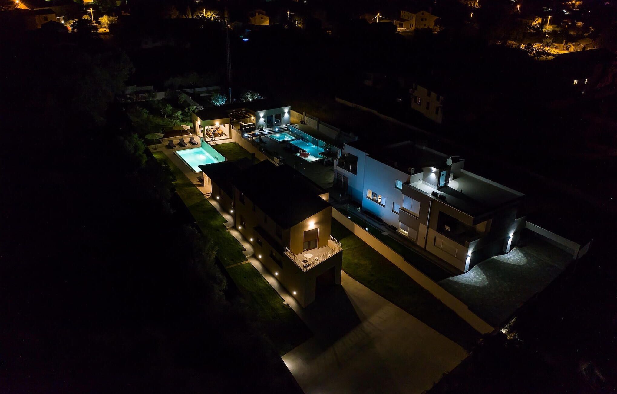A modern house with a swimming pool, outdoor seating, and a well-lit patio area.