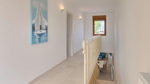 A staircase with a view of a dining area and a painting of a sailboat on the wall.