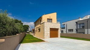 A modern residential building with a stone facade, a wooden garage door, and a clear blue sky.