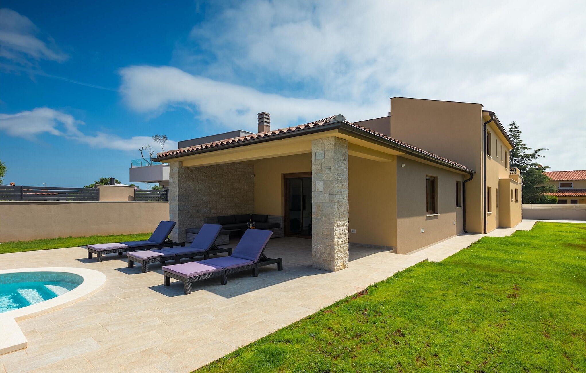 Une maison moderne dotée d’un patio couvert, d’une piscine et d’une pelouse bien entretenue.