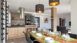 A modern dining area with a wooden table set for six, surrounded by black chairs. A kitchen with a marble backsplash and stainless steel appliances is visible in the background. - Awesome home in Svetvincenat (Svetvincenat)