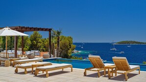 A poolside area with lounge chairs and a pergola overlooking the sea. - New Villa/Amazing sea views/close to City and Beach/Heated pool/Sauna/Gym (Hvar)