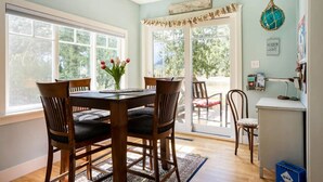 A dining area with a table and chairs, a vase of flowers, and a view through the glass door.