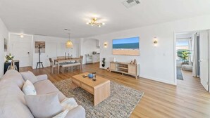 A spacious living area with a sofa, coffee table, and dining table. There is a painting on the wall and a view of the outdoors. - Casa Aurelia by Oraklus (Malibu)