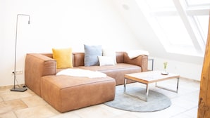 Un salon moderne avec un canapé en cuir marron, une petite table ronde et un lampadaire.