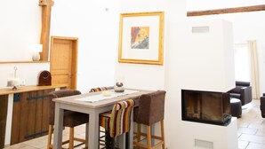 Un coin repas avec une table et des chaises en bois, une cheminée et un tableau encadré au mur.