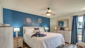 A bedroom with a bed, nightstands, a dresser, a ceiling fan, and decorative wall art.