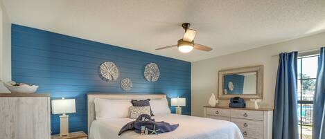 A bedroom with a bed, nightstands, a dresser, a ceiling fan, and decorative wall art.