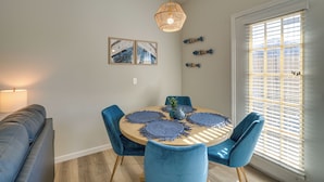 A dining area with a round table, blue chairs, and a hanging light fixture.