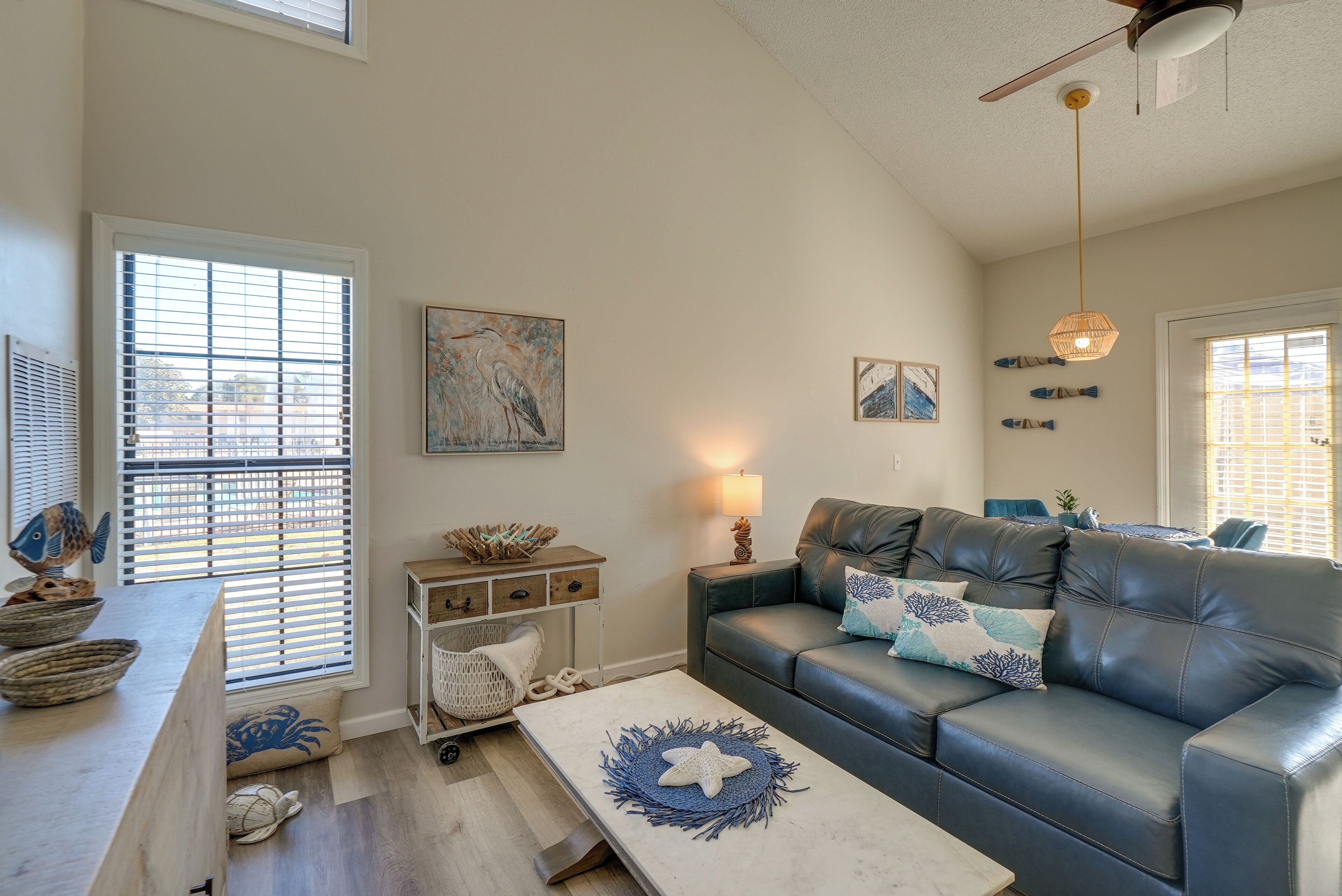 A living room with a blue leather sofa, a white coffee table with a starfish decoration, and a wall-mounted lamp.