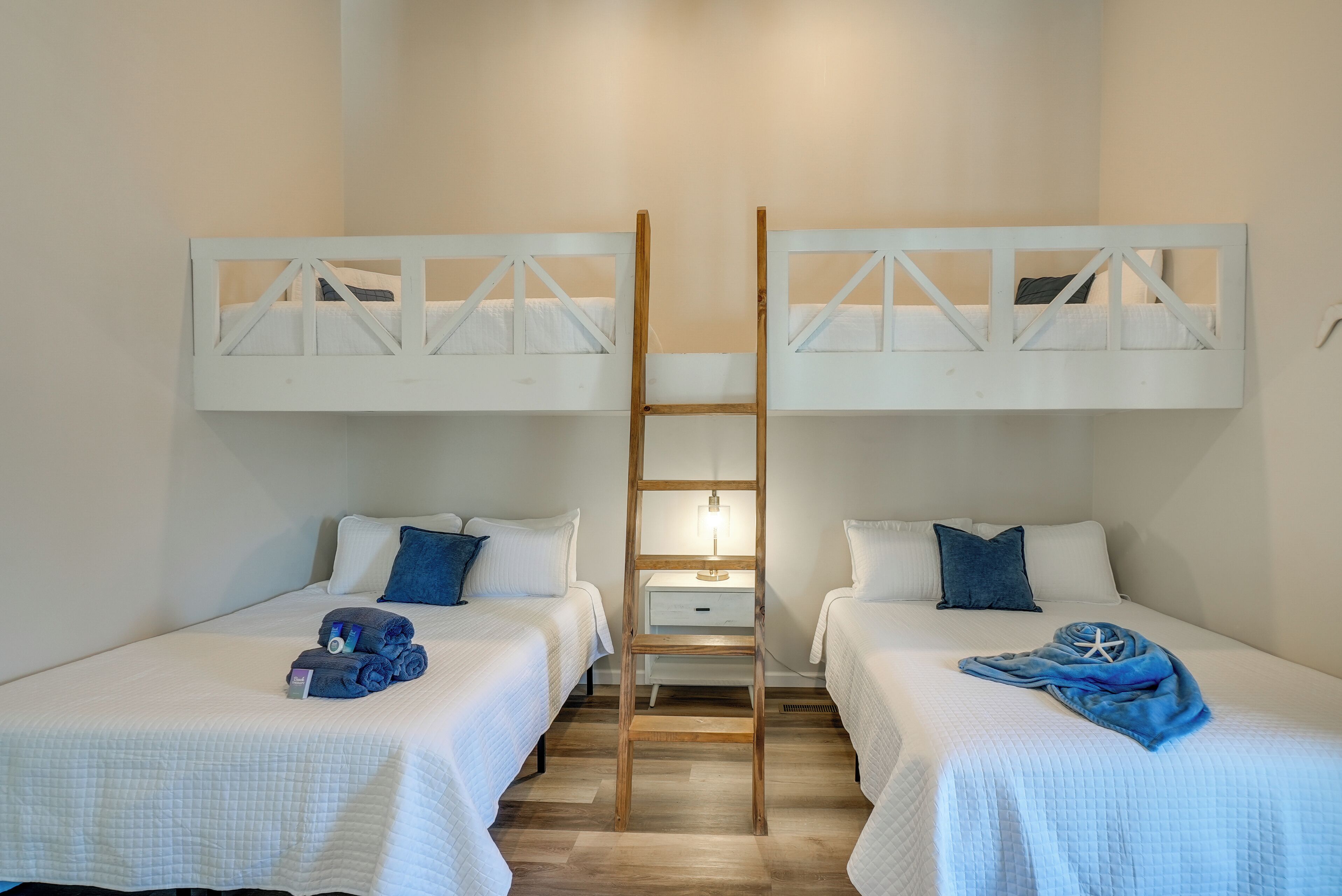 A room with two beds, each with a wooden ladder, a bedside table, and a lamp.