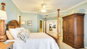 Une chambre à coucher avec un lit à baldaquin, une tête de lit en bois et une table de chevet avec une lampe.