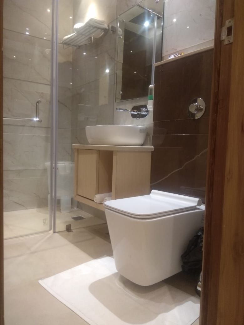 A modern bathroom with a glass shower enclosure, a white toilet, a wooden vanity with a sink, and a mirror above the vanity.