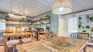 A rustic kitchen with wooden furniture, hanging lights, and shelves with kitchenware.