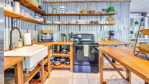 A kitchen with wooden shelves, a sink, and a stove.