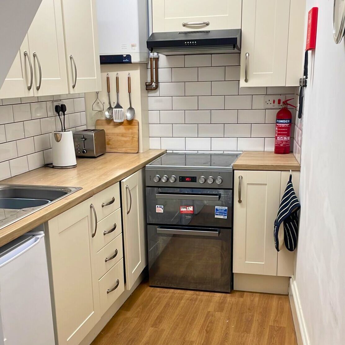 A compact kitchen with a stove, oven, and a toaster.