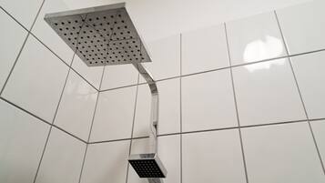 A showerhead with a square head and a curved handle, mounted on a tiled wall.
