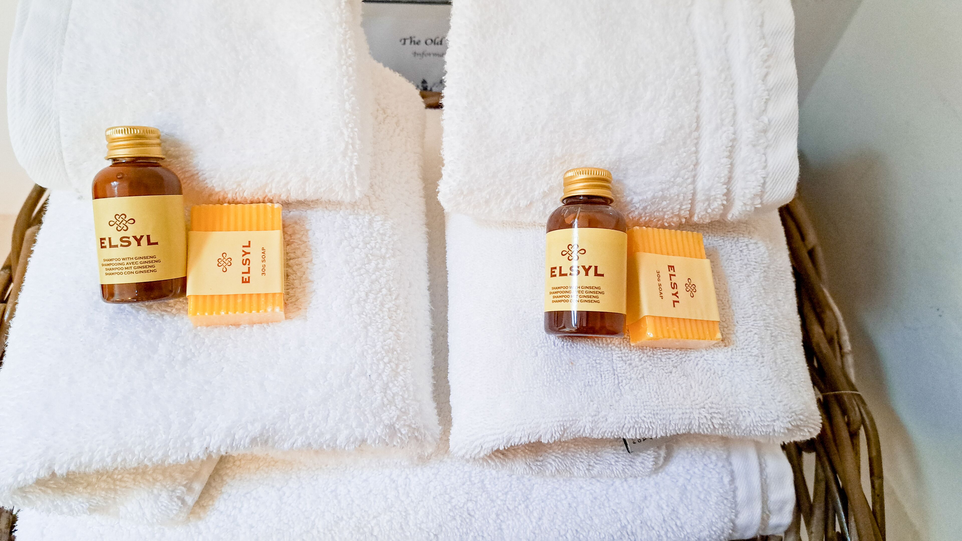 Two white towels with bottles of ELSYL shampoo and soap placed on them.
