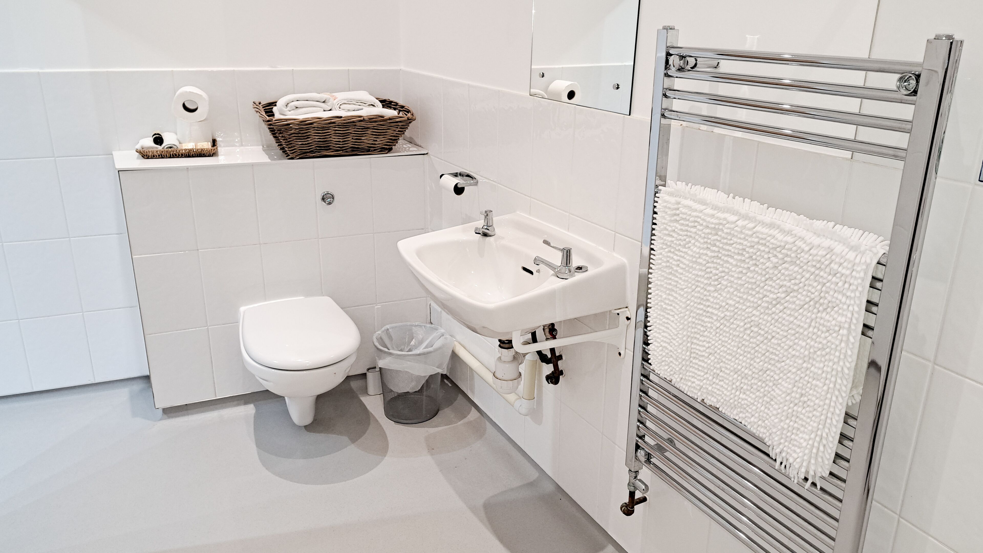 A compact bathroom with a toilet, sink, and towel rack.