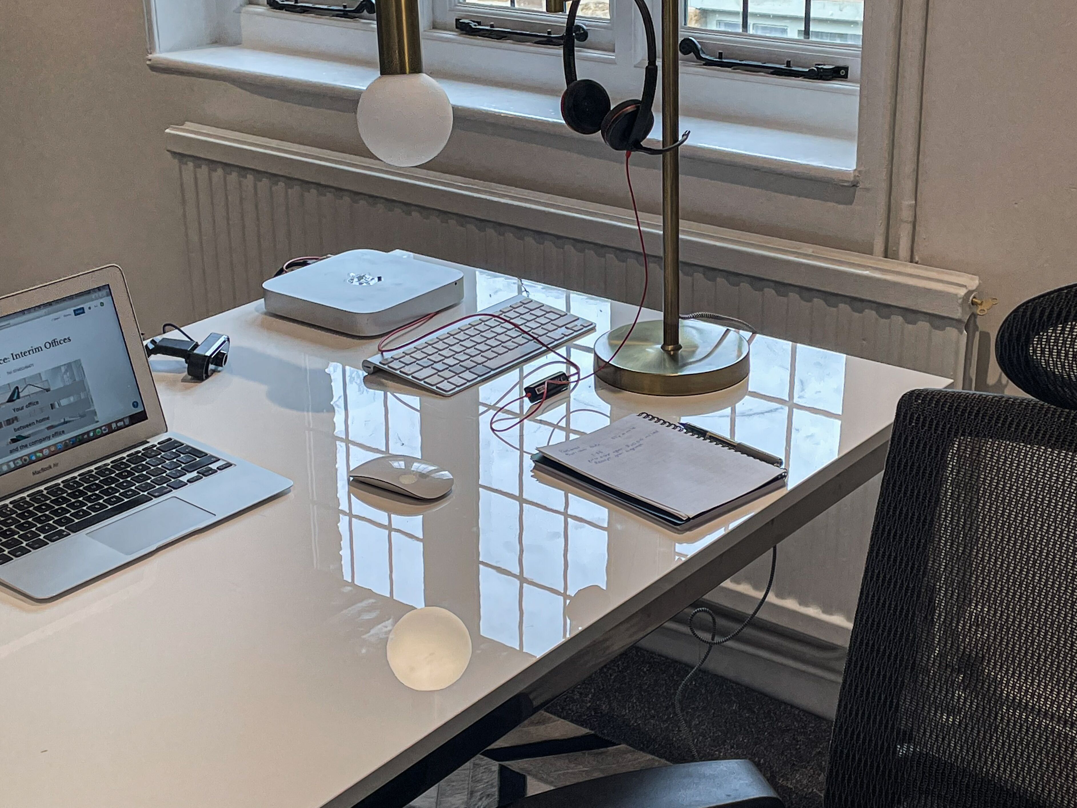 Un bureau moderne, équipé d’un ordinateur portable, d’un ordinateur de bureau, d’un clavier, d’une souris, d’une lampe et d’un carnet.