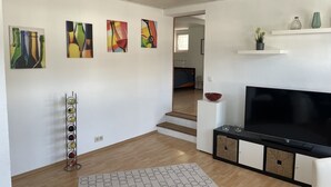 Un salon moderne doté d’un téléviseur à écran plat, d’un meuble à vin et d’œuvres d’art abstraites accrochées aux murs.