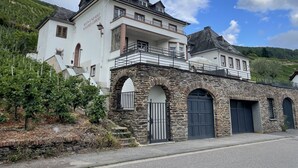 Un grand bâtiment blanc à la façade en pierre, doté de nombreuses fenêtres et d’un balcon.