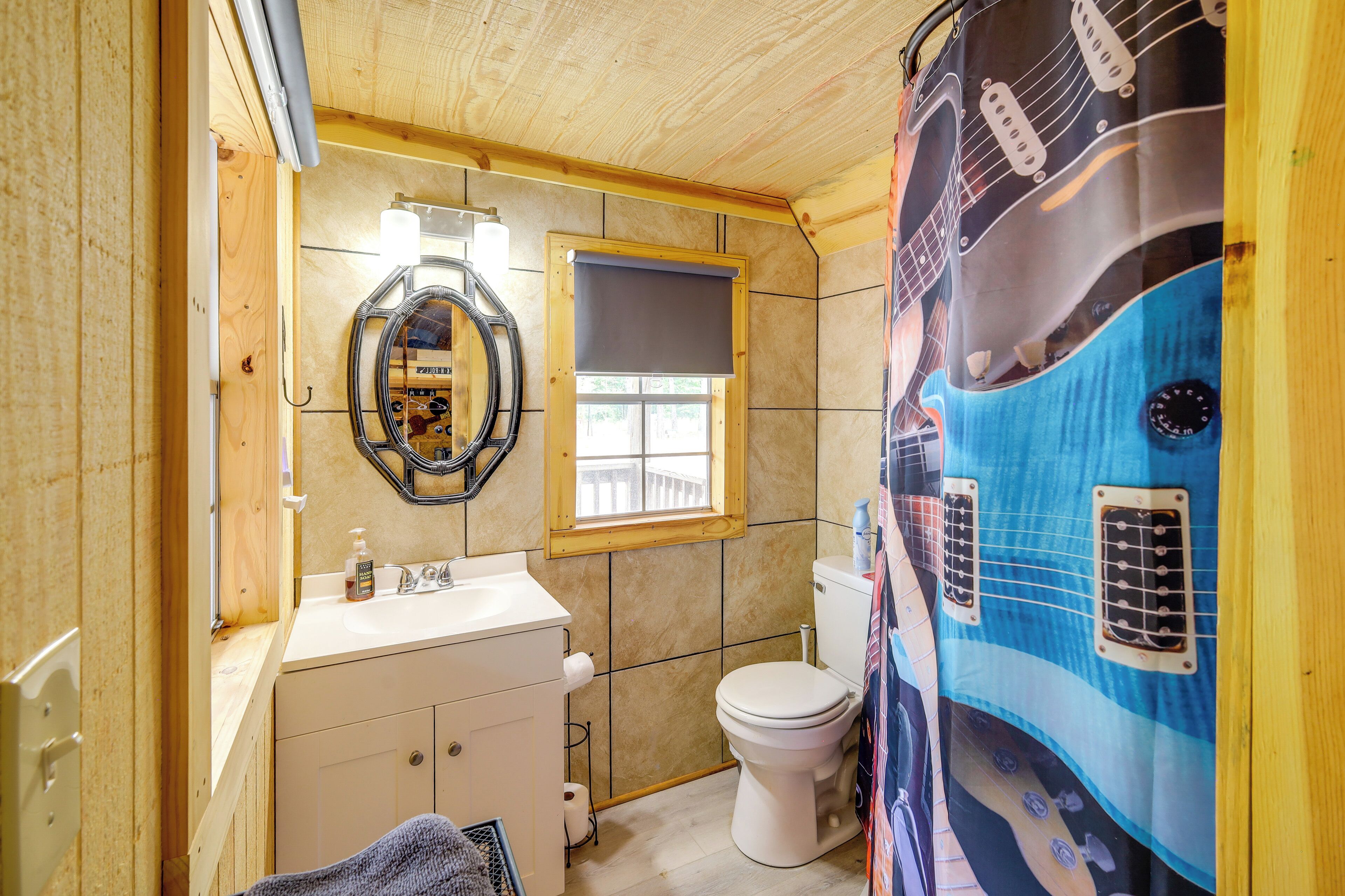 Une salle de bain avec un plafond en bois, un lavabo blanc, des toilettes et une fenêtre.